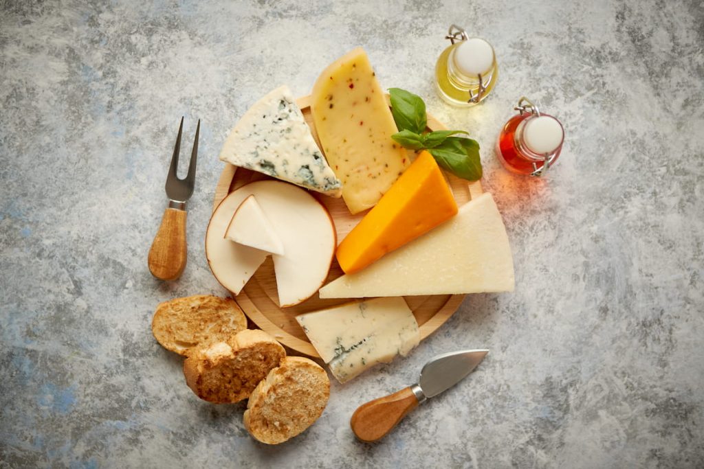 various types of cheese served on rustic wooden plate 